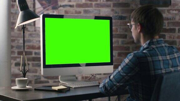 一个年轻人正在电脑前工作电脑上有一个绿色屏幕的模型
