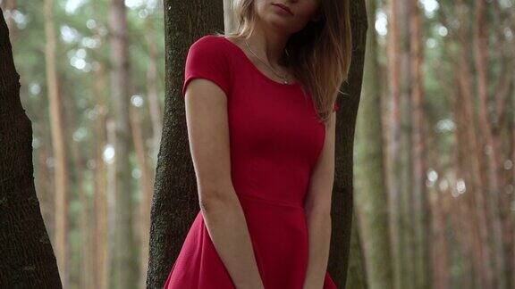 一个穿着红色连衣裙的漂亮时髦的女人走过森林