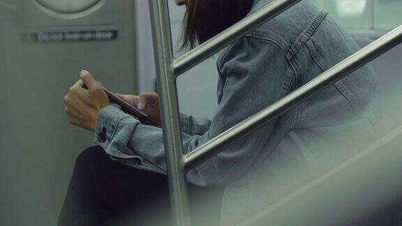 年轻漂亮的女人在公共交通工具上使用智能手机