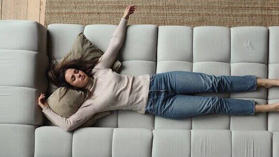 疲惫的年轻女人睡在舒适的沙发上