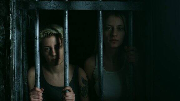 两个拿着铁栏的女人在牢房里张望