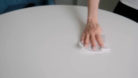慢动作:女人用湿巾擦拭白色桌子消毒概念