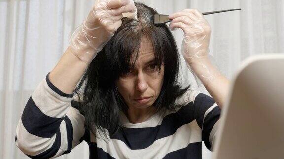 在家染发一位中年妇女正准备在家染发看着她乌黑的头发重新长出的灰色根茎