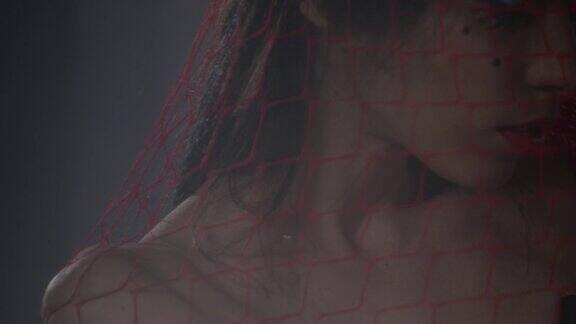 性感的黑发时装模特被困在一个红色的网显示面部表情时尚视频