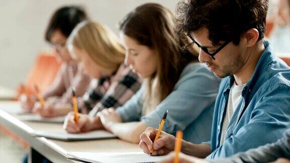 教室里的一排多民族学生在考试测试写笔记本聪明的年轻人在大学学习