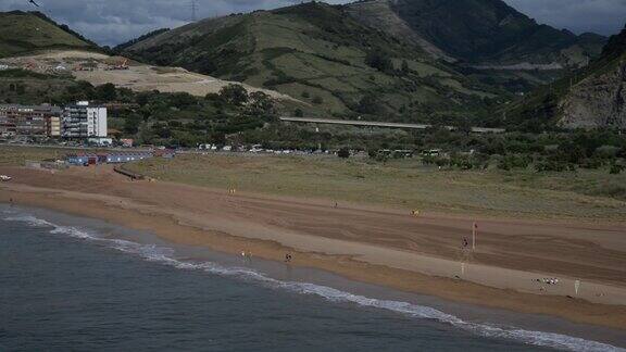 海滩上的人们的鸟瞰图波浪般的大海和地平线上的青山