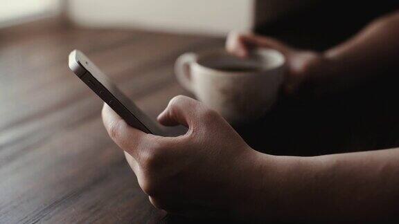 一个女人正在近距离的咖啡馆里喝着咖啡并在手机上输入一条信息