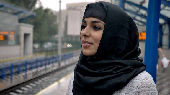 年轻梦想的穆斯林妇女在等待火车宗教观念城市观念