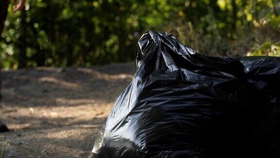 黑色塑料袋里装着垃圾在森林里的路上