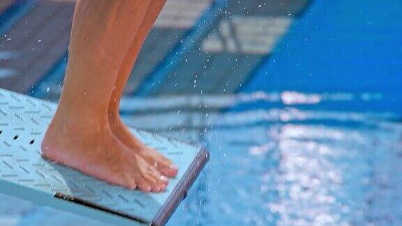 一位女跳水运动员在阳光下从跳板上跳下的脚