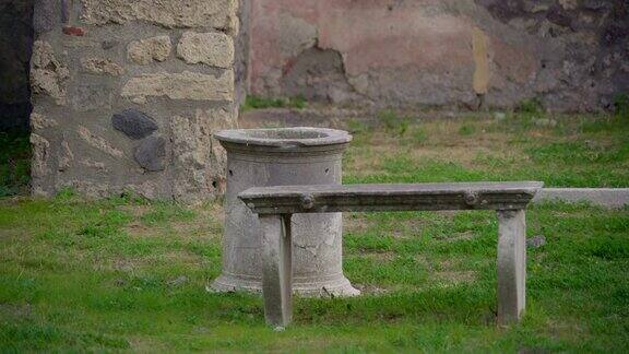 在意大利庞贝的草坪上一个小水泥桶和一条长凳