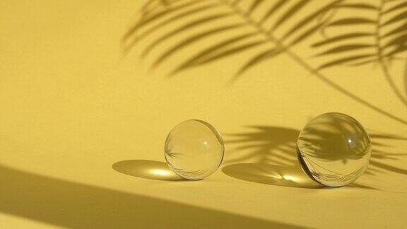 摘要背景与玻璃球在黄色背景与太阳反射和棕榈叶阴影