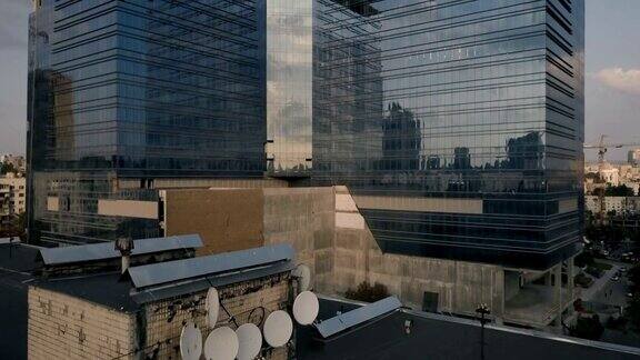 玻璃幕墙的摩天大楼靠近旧的多套公寓大楼镜头从旧房子移到新楼鸟瞰图