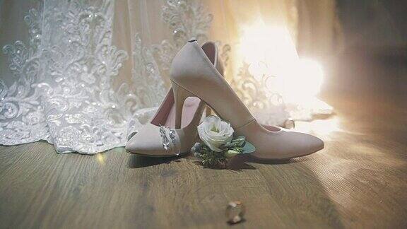 两个结婚戒指在新娘的结婚鞋附近滚动
