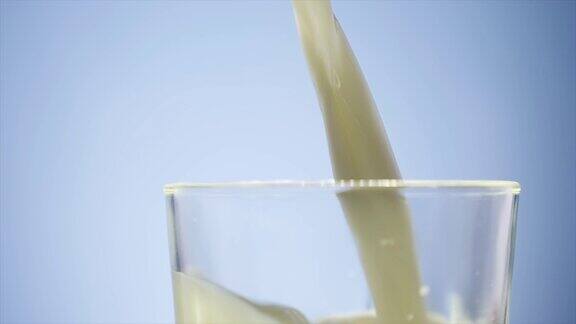往玻璃杯里倒牛奶白牛奶装满透明的玻璃杯牛奶倒在前面的白色背景