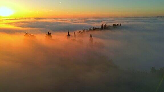 日落时分浓雾笼罩着山顶上的教堂