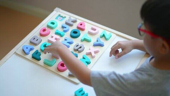 亚洲男孩学习英语字母玩具和字母表重返校园