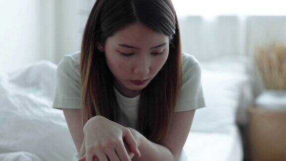 抑郁和心理问题年轻的亚洲女人独自坐在床上她感到孤独和不快乐