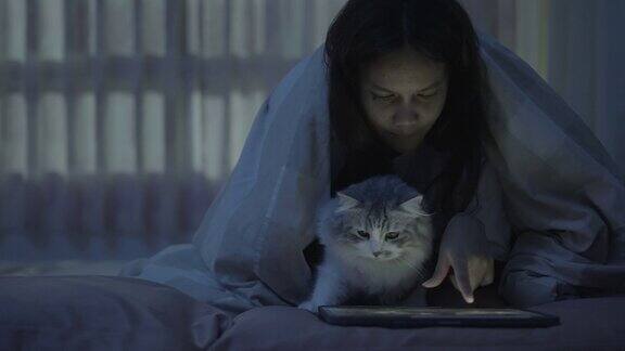 年轻妇女和她的猫在床上使用药片