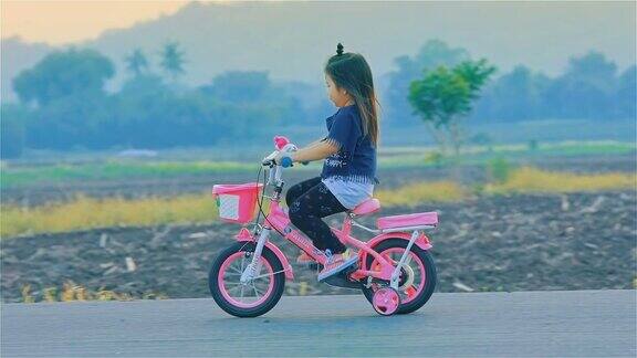 在乡下骑自行车的亚洲小女孩