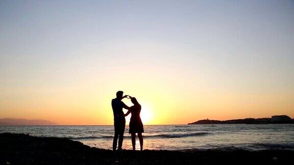 日落时分一对情侣在海滩上拥抱