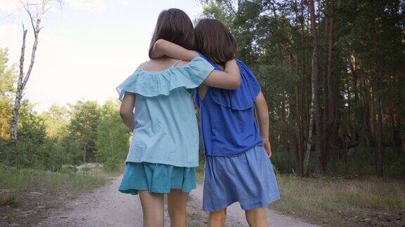 两个可爱的女孩走在林中小路上聊天
