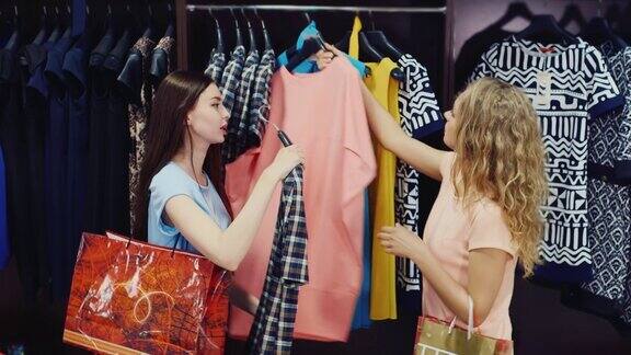 两个漂亮的女人走在衣架旁边看着衣服