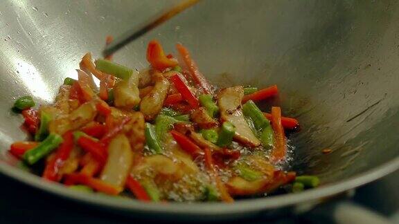 厨师用滚烫的油煎锅准备新鲜的蔬菜用木铲搅拌