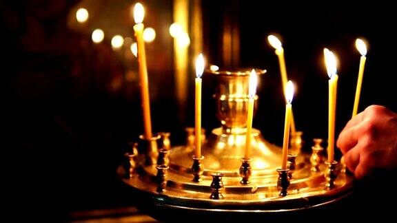 在基督教教堂的圣面前人们在烛台上纠正燃烧的蜡烛
