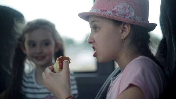 两姐妹坐上一辆旅游巴士望着窗外吃着苹果