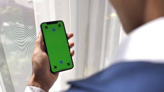 商人看智能手机与绿色屏幕手持智能手机iPhoneX