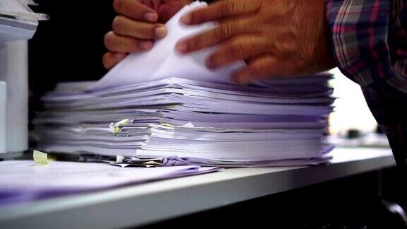 会计计划预算概念:商务女性办公室工作中整理文件未完成的堆文件用纸用笔夹在繁忙的办公桌上