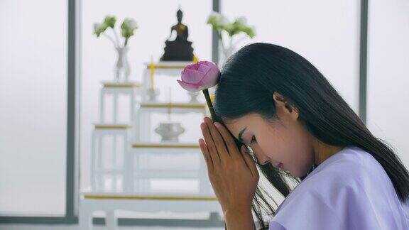 抱着莲花向佛祈祷的亚洲佛教妇女