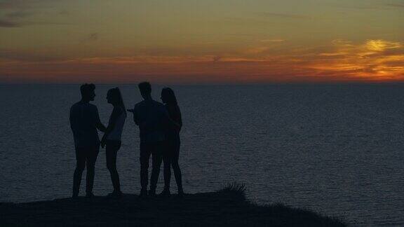 夕阳下四个朋友站在海边