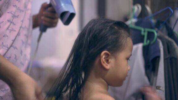 亚洲母亲用染发器吹干她女儿的头发