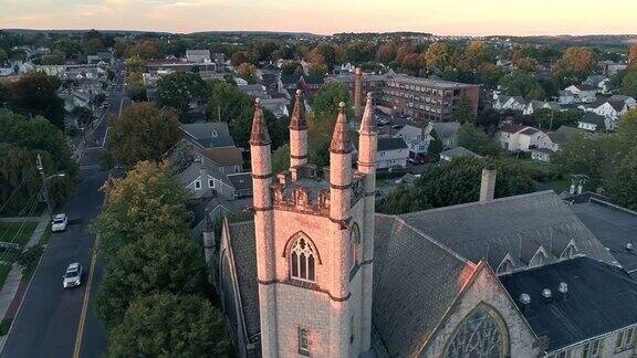 风景鸟瞰拿撒勒宾夕法尼亚州和他的教堂在日落无人机视频与全景轨道复杂的电影摄像机运动中世纪风格的圣约翰联合基督教堂为主要焦点