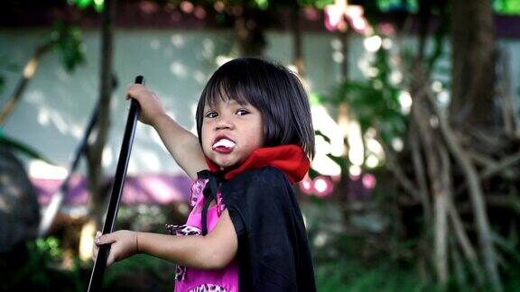 小女孩穿着吸血鬼服装在镜头前摆姿势化妆成万圣节的恶魔