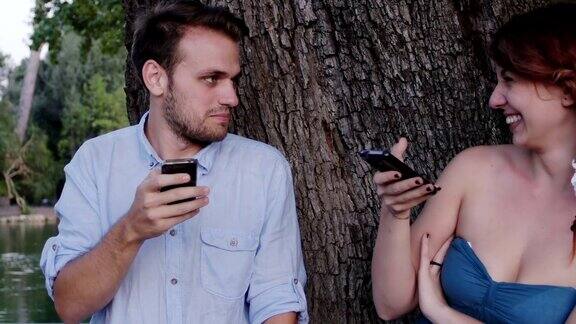 一对订婚的情侣在公园里用手机聊天