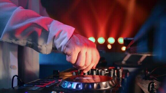 DJ男性双手混合音乐调节唱盘控制台控制CD照亮夜总会派对
