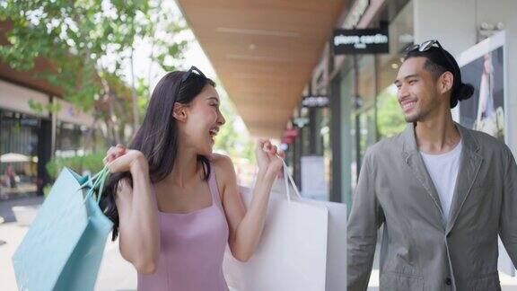 亚洲青年男女在百货公司户外购物迷人的情侣拿着购物袋然后幸福地走在一起享受购物中心购物