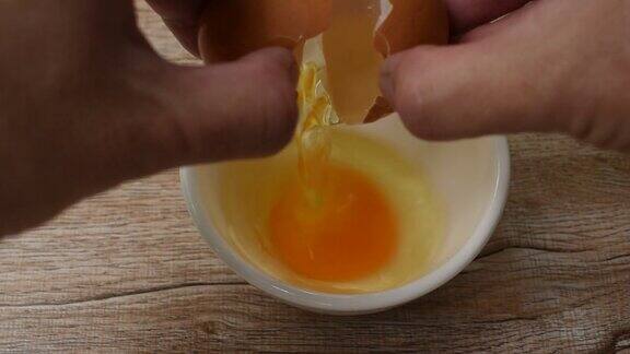 手打开蛋壳生鸡蛋和蛋黄掉进去
