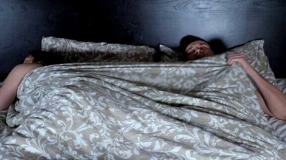 年轻夫妇正在睡觉争夺毯子