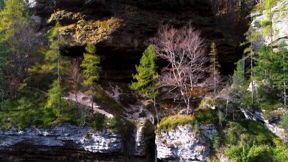美丽的瀑布和古老的岩石在绿色的秋天森林鸟瞰山景蓝色的池塘和流动的河流
