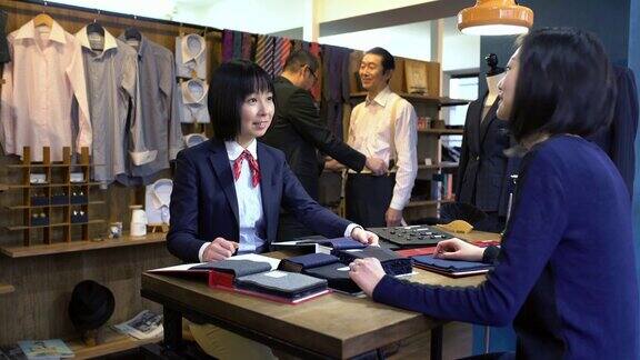 一位高级西服店里的女裁缝正在和一位顾客交谈