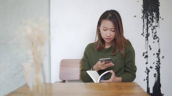 一个亚洲女人在咖啡馆边喝冰咖啡边看书