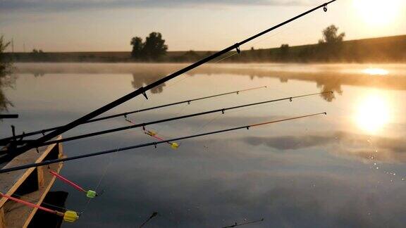 日落河上的钓竿钓竿在清晨天空的背景雾笼罩着池塘