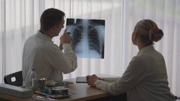 医生坐在办公桌上解释女病人肺部的症状