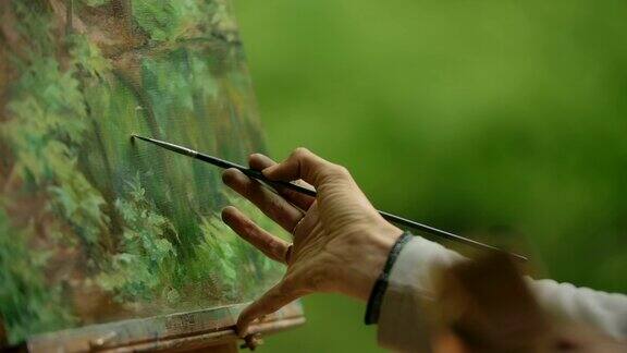 一个女孩的手的特写一个艺术家用画笔在绘画上做最后的润色