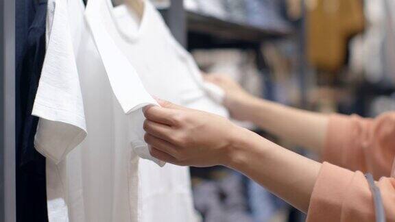 女性手拔衣架在服装店挑选衣服的特写在一家购物中心一个女人的手跑过一架买衣服的衣服促销和购物概念
