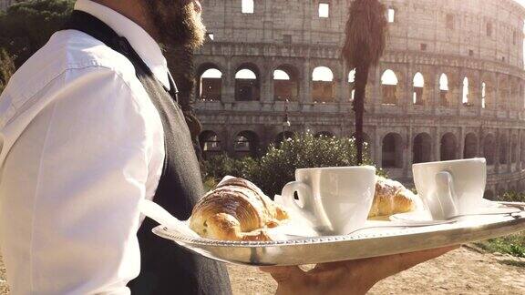 日落时分在罗马斗牛场前优雅的侍者端着早餐牛角面包卡布奇诺